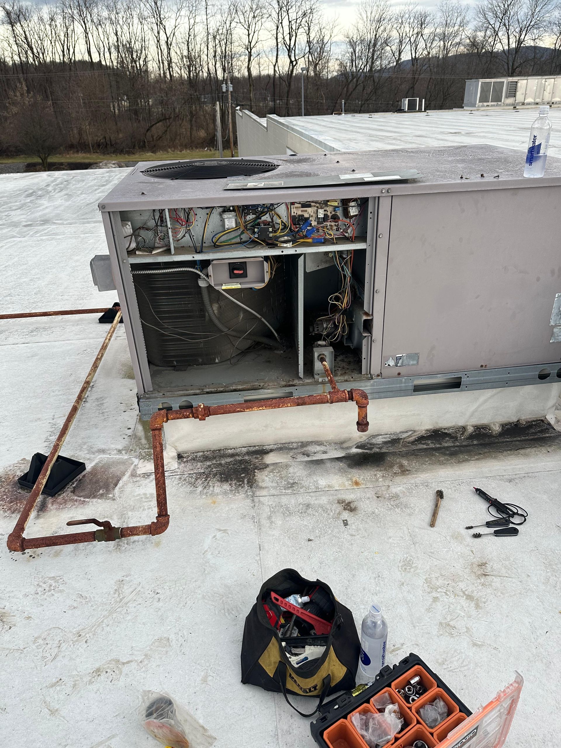 HVAC unit on a rooftop being serviced, showing interior components and tools.