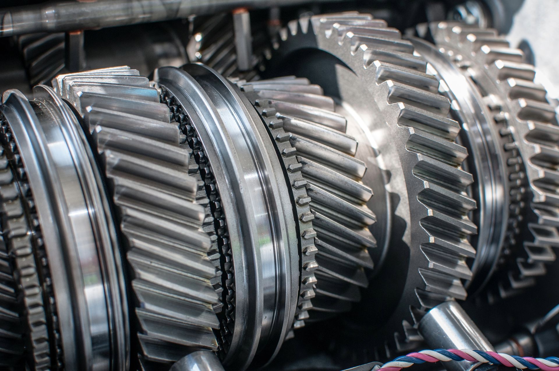 Close-up of shiny metal gears meshing together inside of a machine.