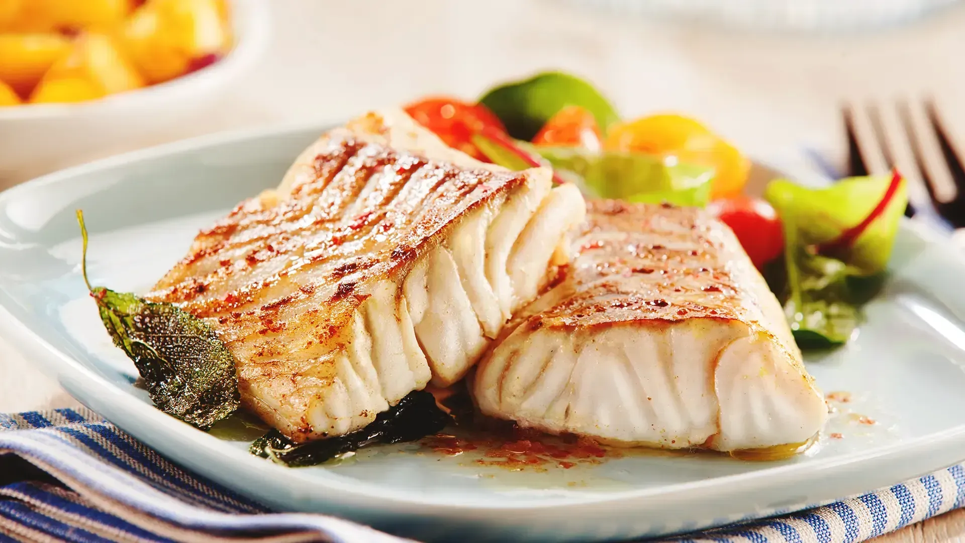 Dois filés de peixe cozidos com legumes em um prato.