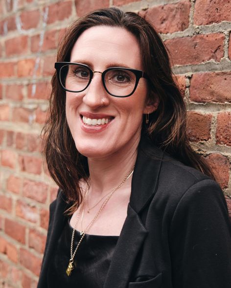 young female women in black turtleneck with arms crossed standing in front of a graffiti wall