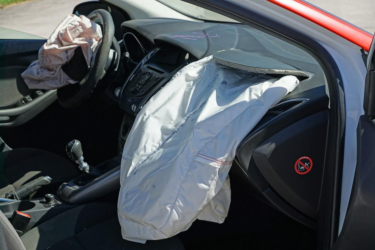 Deployed airbags inside a car after a collision; dashboard and steering wheel visible.