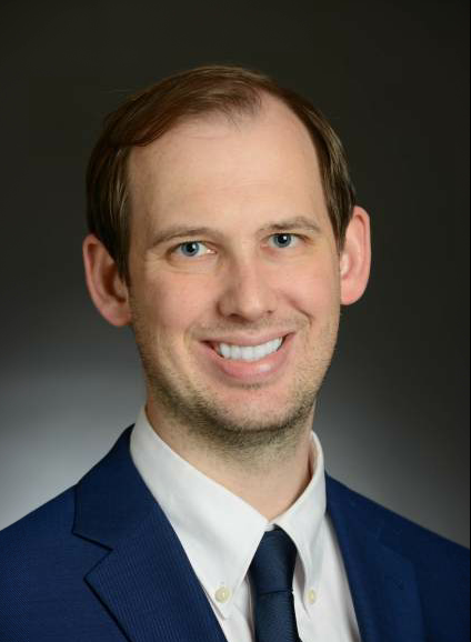 A man in a suit and tie is smiling for the camera.