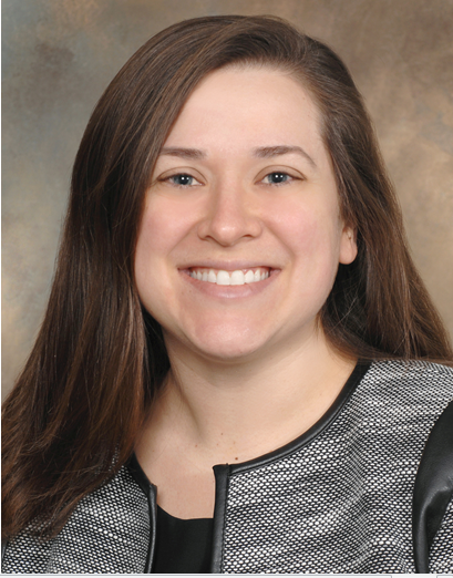 A woman with long brown hair is smiling for the camera.