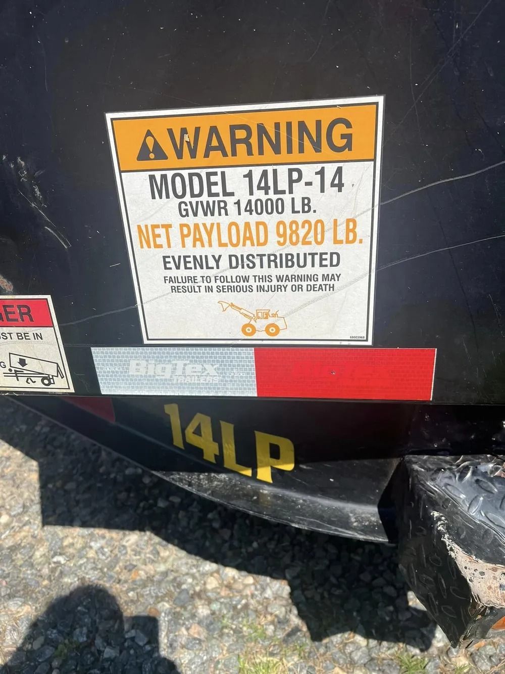A trailer warning sticker displaying model 14LP-14, a 14,000 lb GVWR, and a 9,820 lb net payload capacity.
