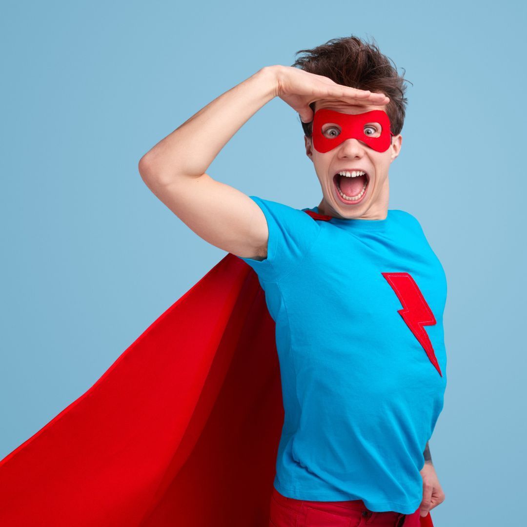 A person in a superhero costume with a red mask and cape, looking into the distance with a surprised expression.