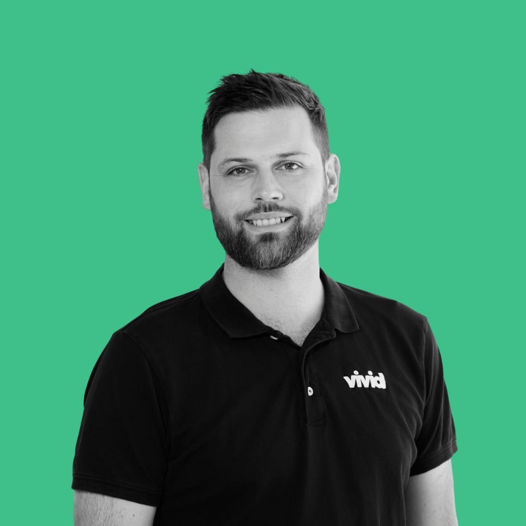 Smiling man in a black polo shirt against a green background