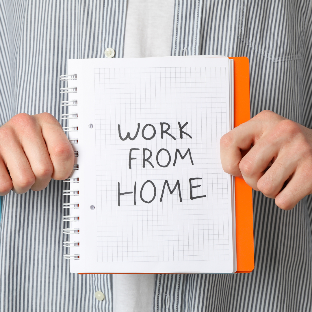 A person in a striped shirt holds an open notebook with the words 