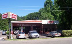 A brake repair shop with a red sign. Cars are parked outside.