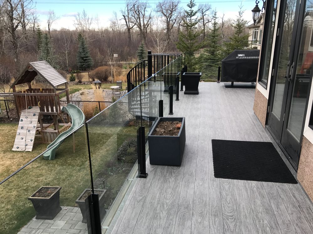 Une terrasse avec une balustrade en verre et des plantes en pot dessus.