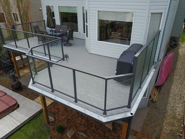 Une vue aérienne d'une terrasse avec une balustrade en verre devant une maison.
