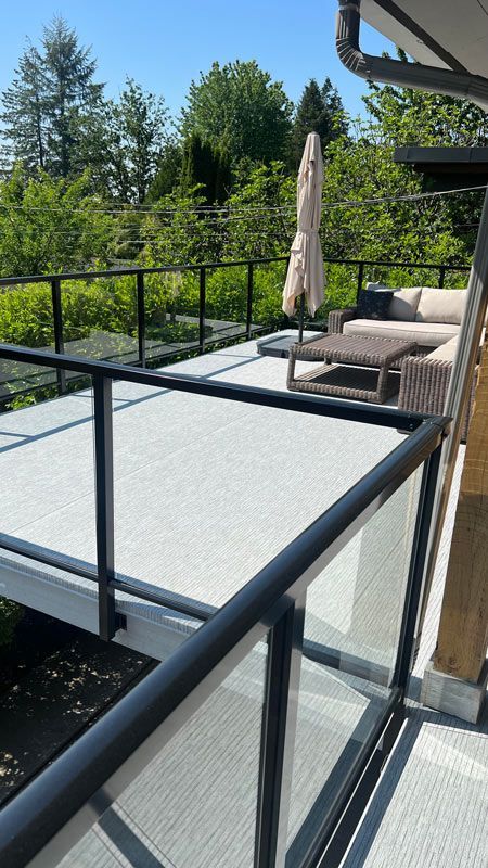 Un balcon en membrane de pvc avec une balustrade en verre, un canapé et un parasol.
