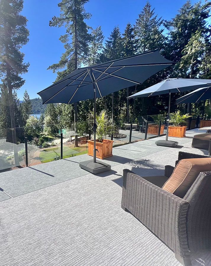 Un patio avec parasols, chaises et vue sur un lac.