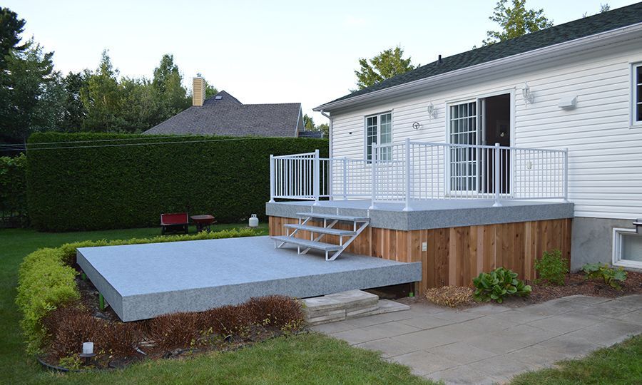 A white house with a deck covered with pvc membrane and stairs in front of it