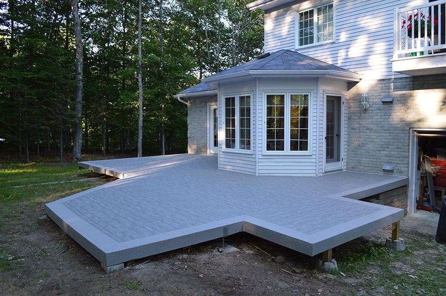 Une grande maison avec une grande terrasse devant elle en membrane de pvc