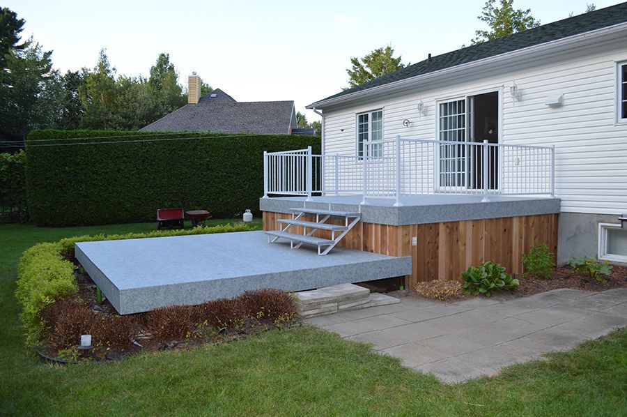 Une maison blanche avec une terrasse en membrane de pvc et des escaliers devant elle