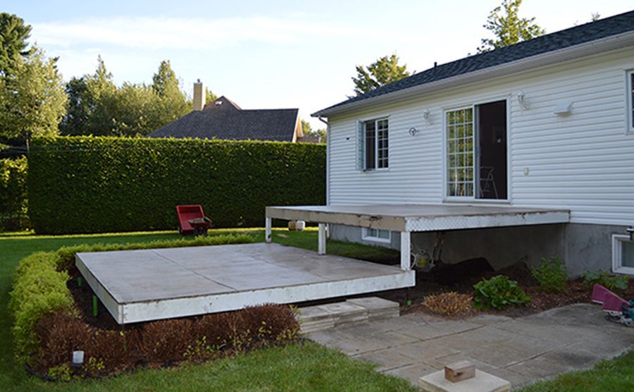 Une maison blanche avec une terrasse en bois devant elle