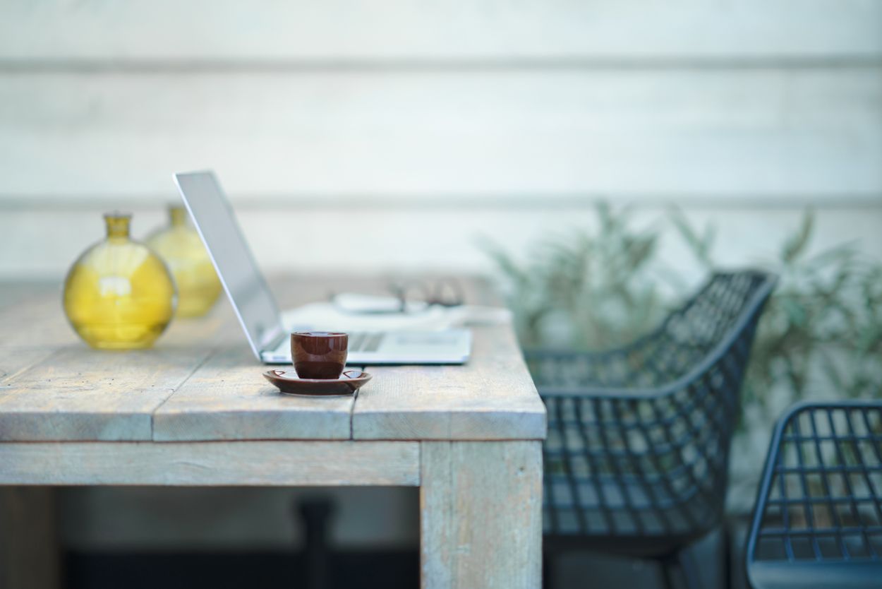 Ordinateur portable sur une table en bois avec un tasse  l'extérieur.