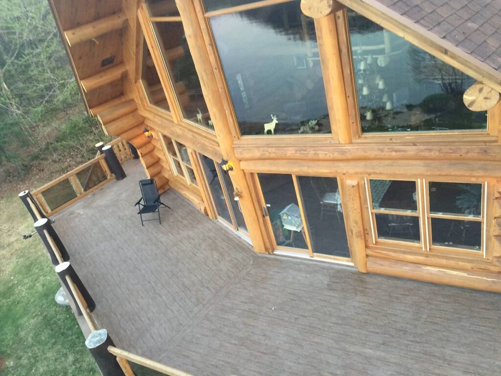 Une vue aérienne d'une cabane en rondins avec une grande terrasse avec membrane de pvc
