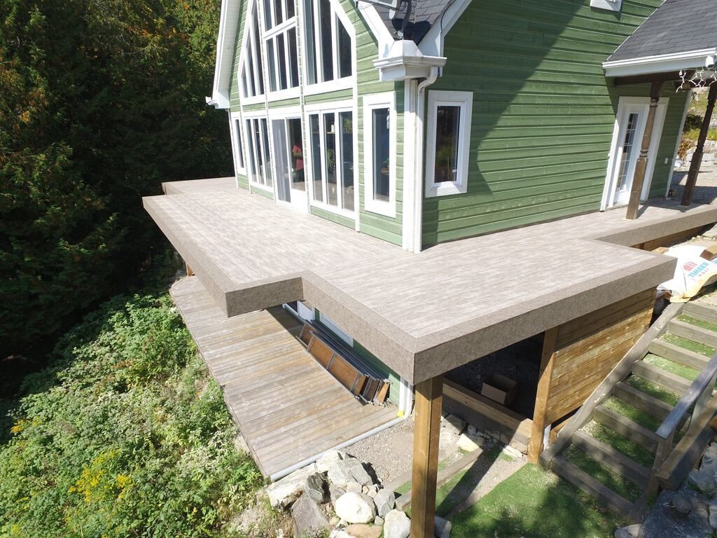 Une vue aérienne d'une maison avec une terrasse en bois couverte d'une membrane de pvc.