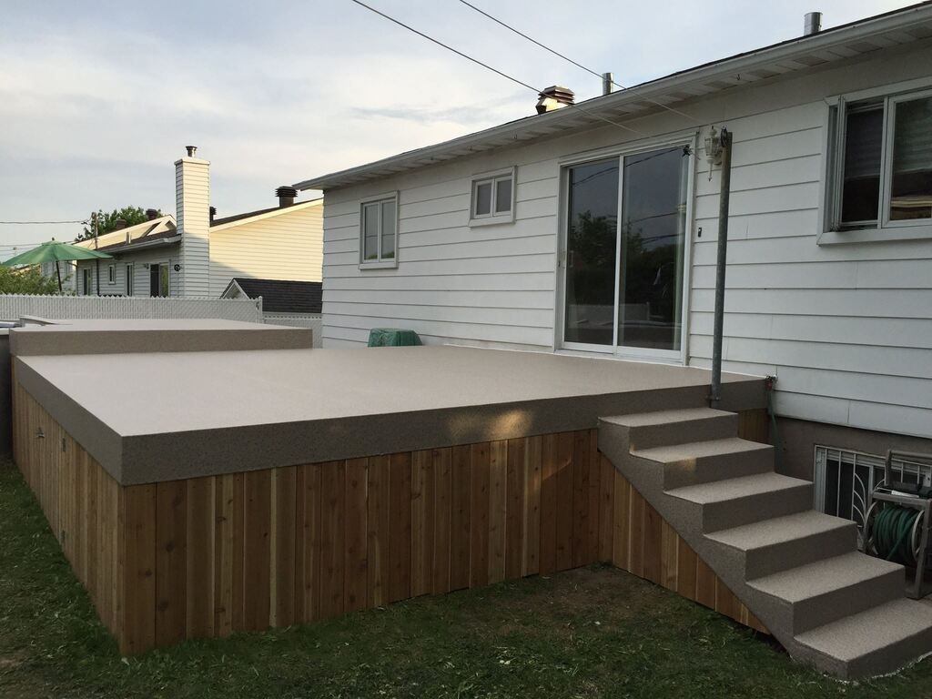 Une maison blanche avec une terrasse en bois couverte d'une membrane de pvc et des escaliers