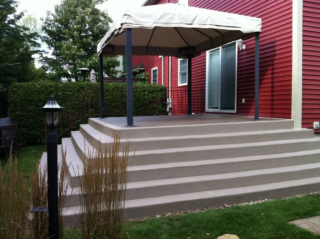 Une maison rouge avec un patio avec des escaliers et un belvédère
