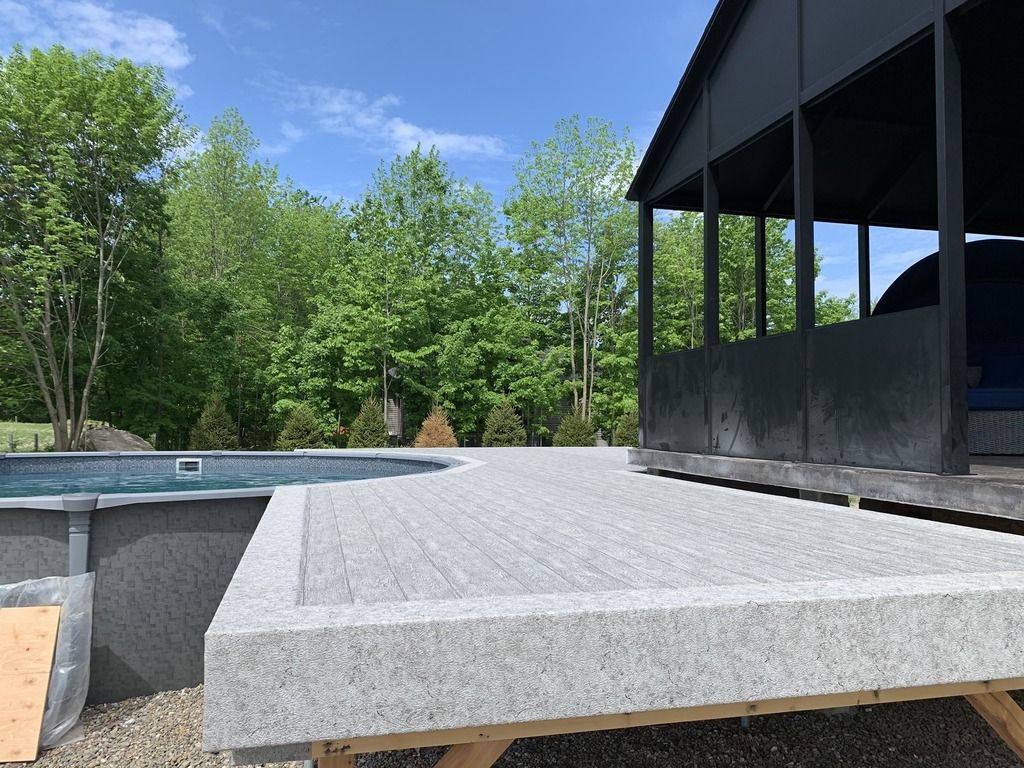Une terrasse en pvc est à côté d'une piscine.