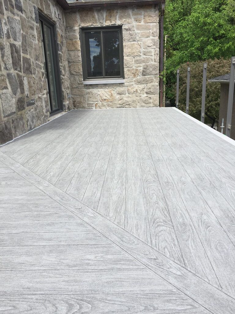 Une terrasse en pvc se trouve devant un bâtiment en pierre.