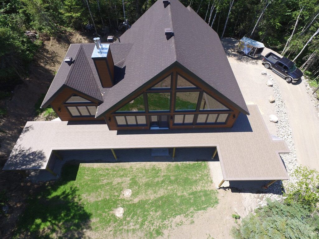 Une vue aérienne d'une grande maison entourée d'arbres avec une grande terrasse avec membrane de pvc