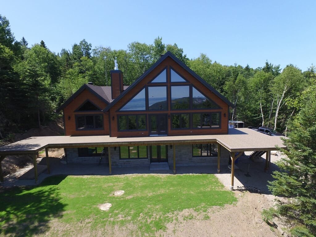 Une vue aérienne d'une grande maison entourée d'arbres avec un patio en membrane de pvc