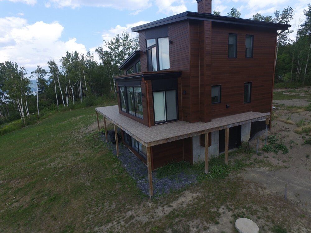 Une vue aérienne d'une grande maison avec une grande terrasse entourée d'arbres.