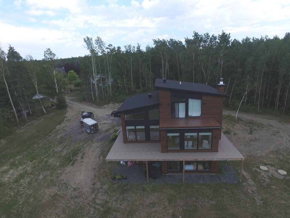 Une vue aérienne d'une maison au milieu d'une forêt avec une grande terrasse