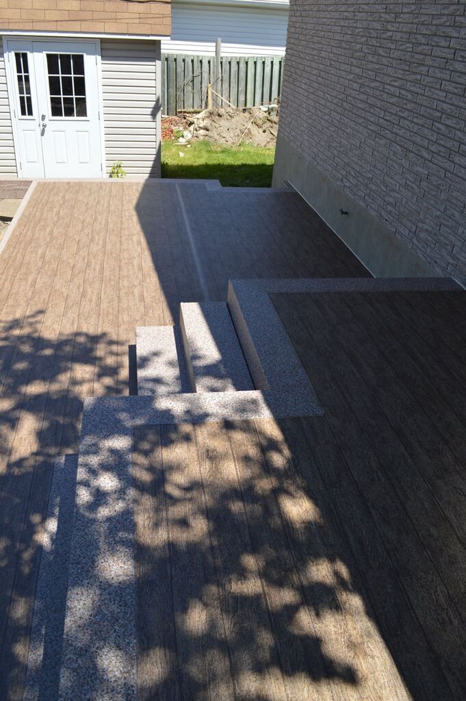 Un patio en membrane de pvc avec des escaliers menant à une maison.