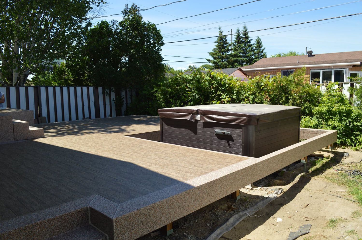 Un spa est posé sur une terrasse recouverte d'une membrane de pvc beige