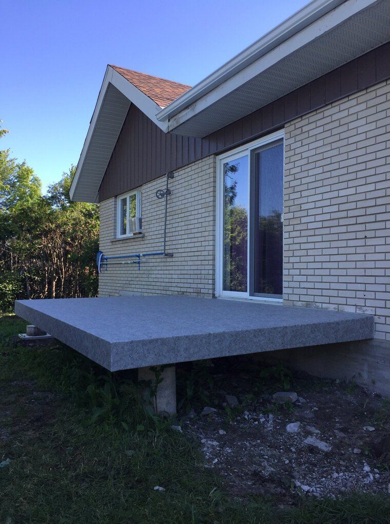 Une maison en brique avec une terrasse en pvc devant.