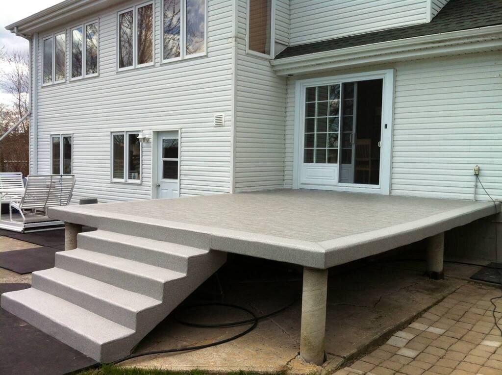 Une maison blanche avec une terrasse en membrane de pvc et des escaliers