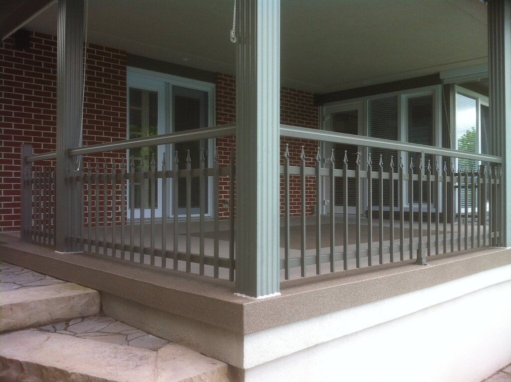 Une galerie avec une balustrade en métal et un mur de briques