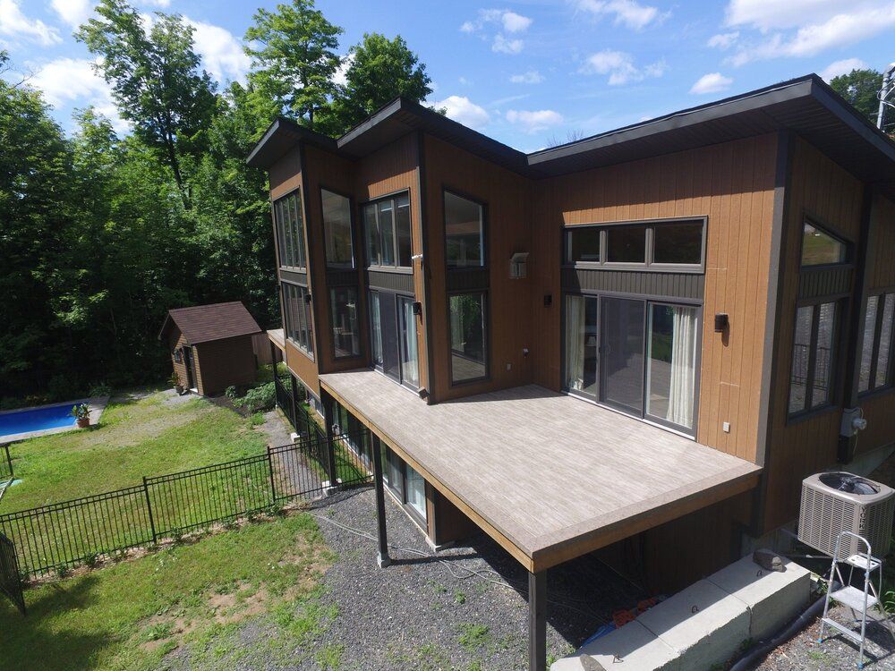 Une vue aérienne d'une maison avec une grande terrasse avec membrane de pvc