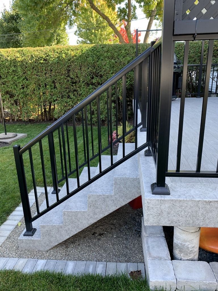 Une balustrade noire entoure un ensemble d'escaliers menant à un patio.