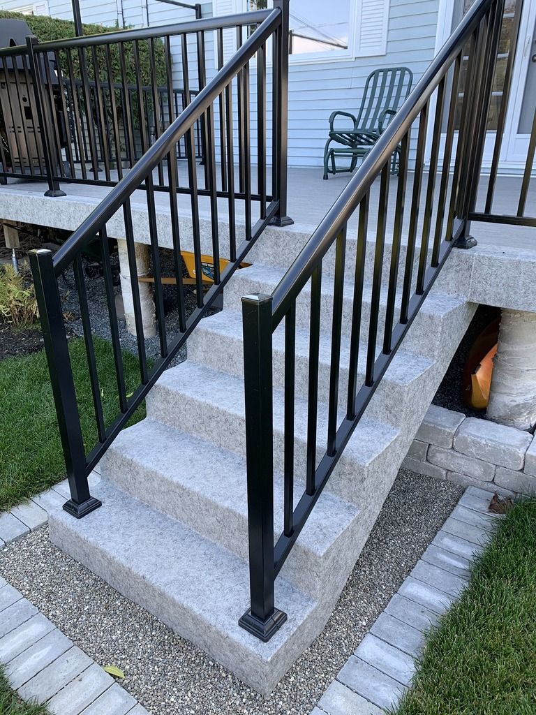 Un escalier avec une rampe noire menant à un porche.