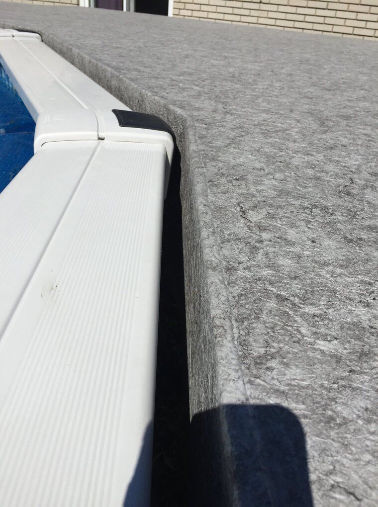 Un gros plan d'une piscine avec le rebord d'un patio en membrane de pvc