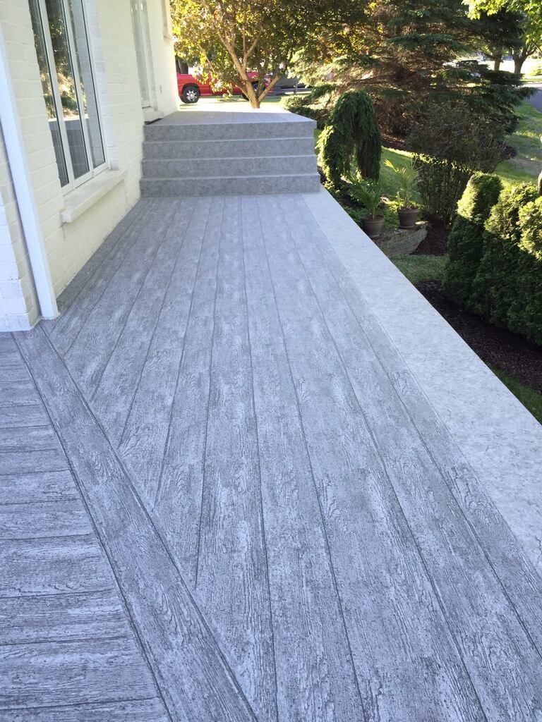 Une terrasse en membrane de pvc avec des escaliers menant à une maison.