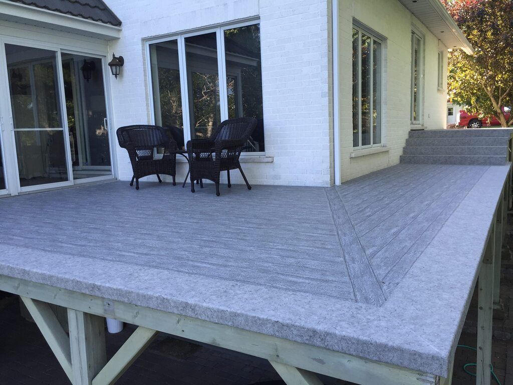 Une terrasse avec des chaises et une table devant une maison.