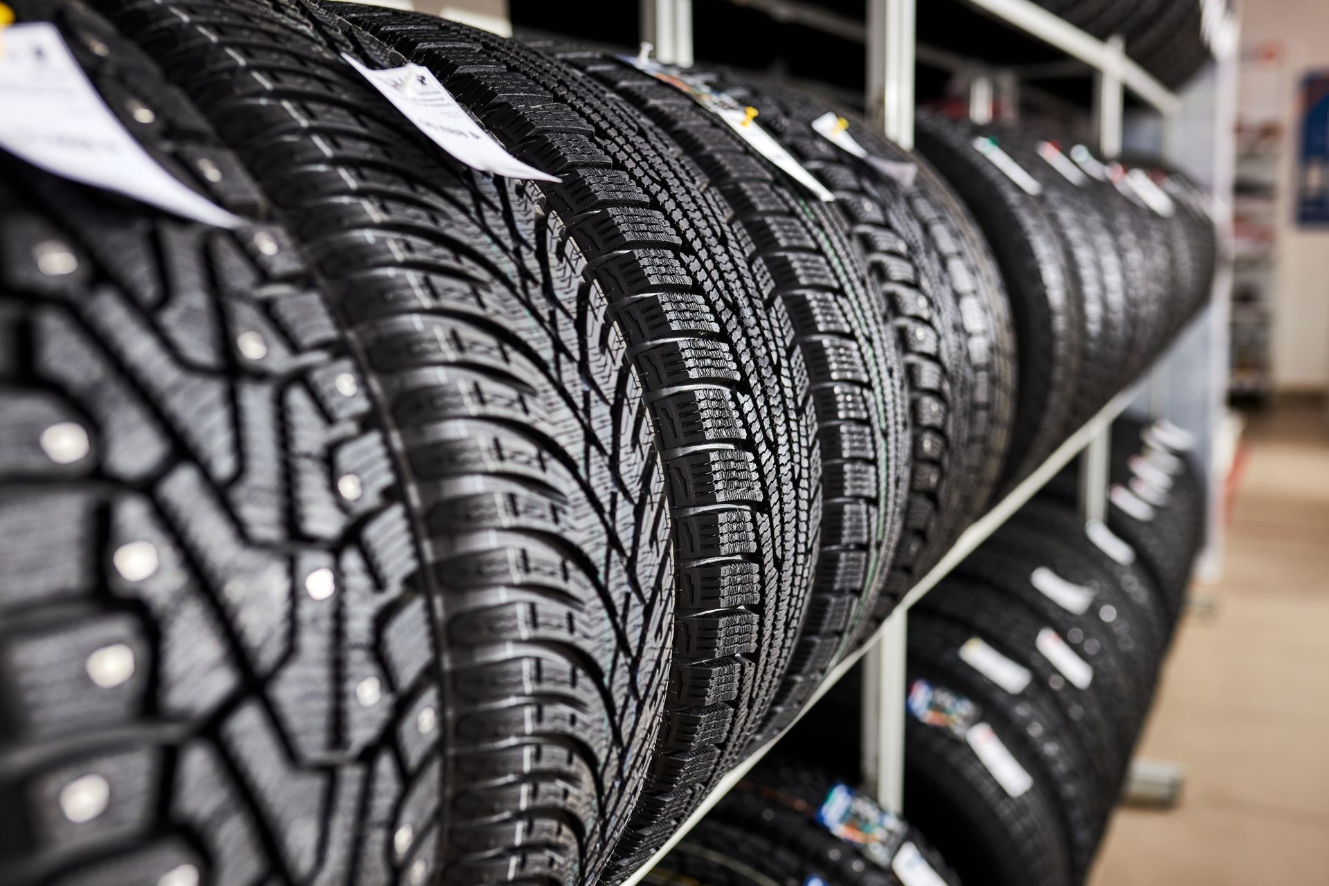 Tires on display in a store, close-up of tread patterns, various sizes, black rubber.