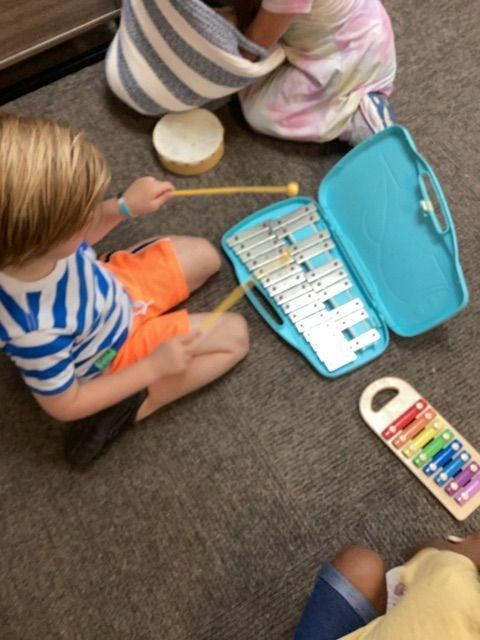 A boy is playing a xylophone and a girl is playing a drum