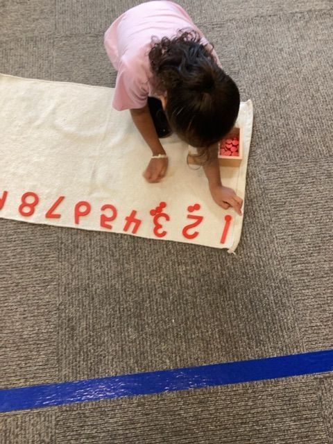 A little girl is playing with numbers on a towel