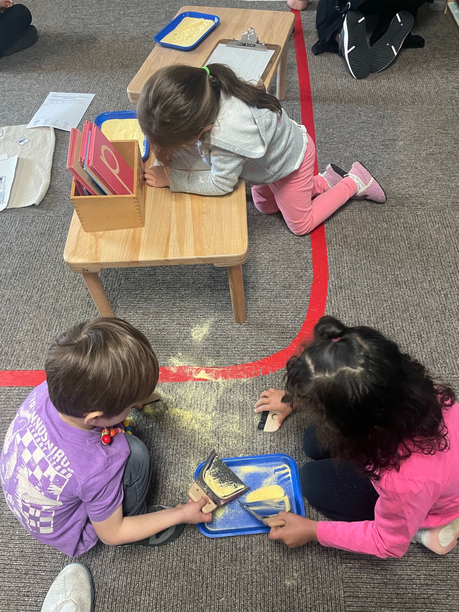 A boy and a girl are sitting on the floor playing with food.