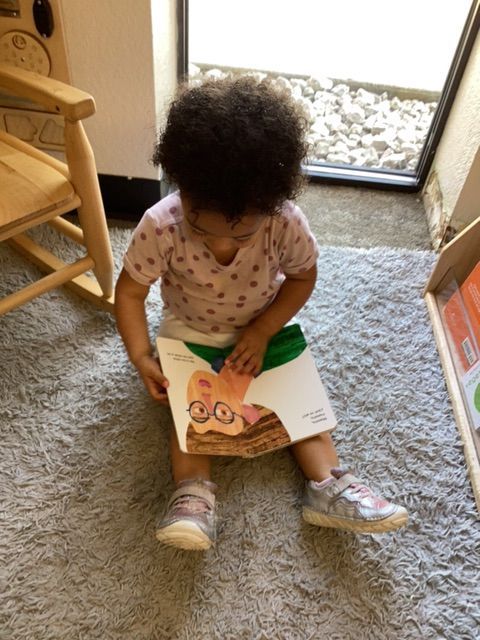 A little girl is sitting on the floor reading a book
