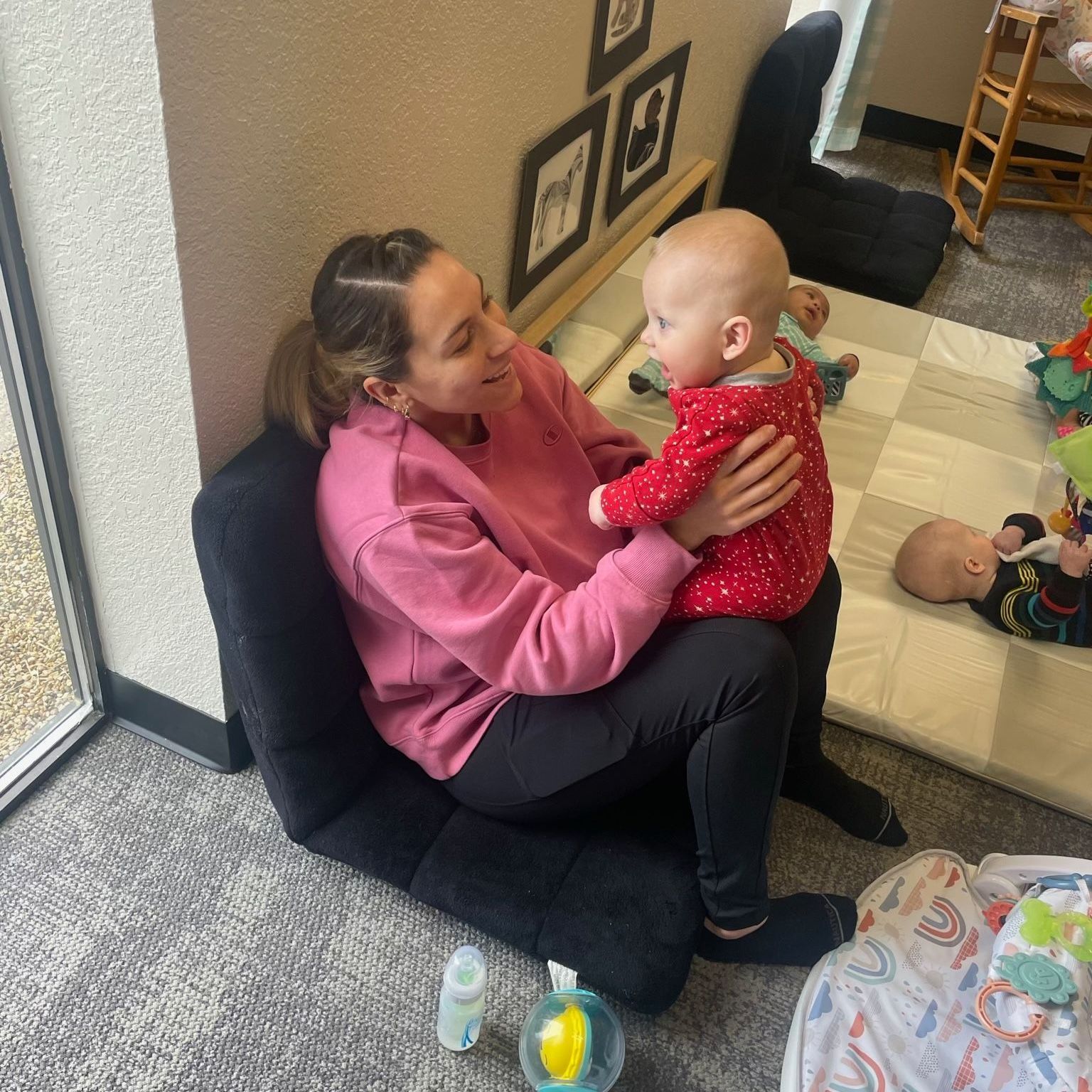 A woman is sitting on a chair holding a baby.