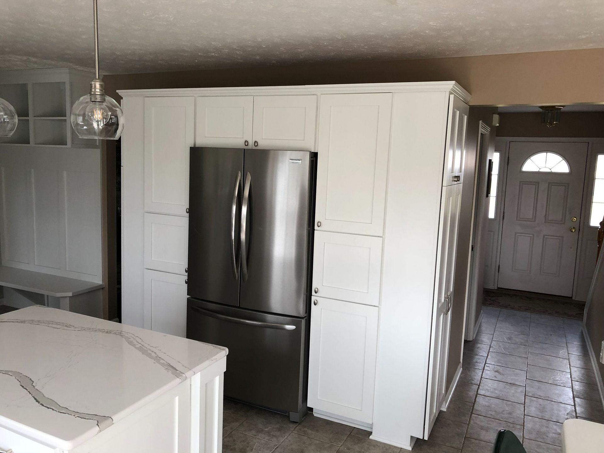 A kitchen with white cabinets and a stainless steel refrigerator