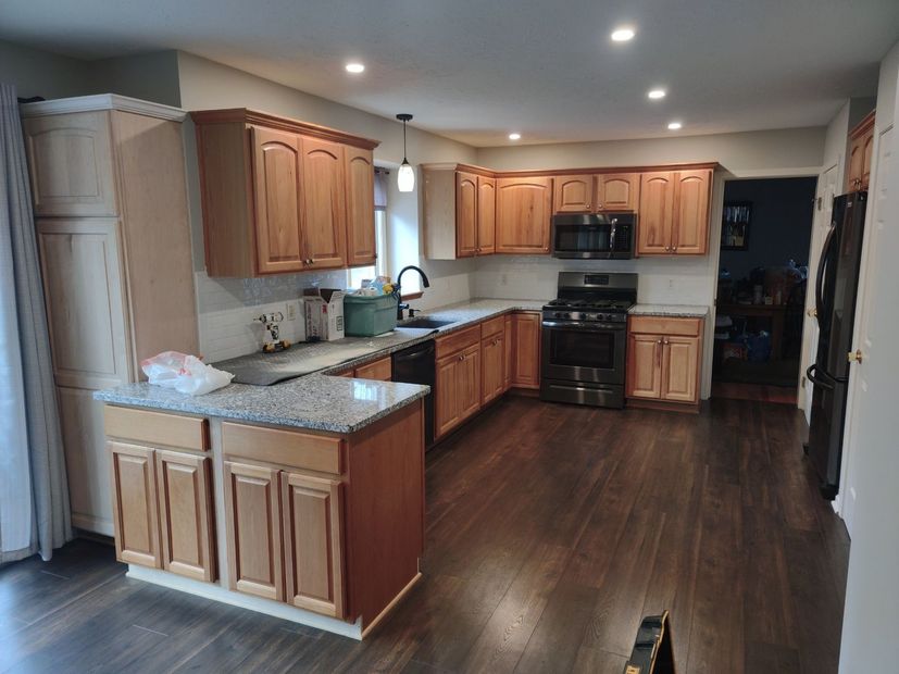 A kitchen with wooden cabinets , granite counter tops , and stainless steel appliances.